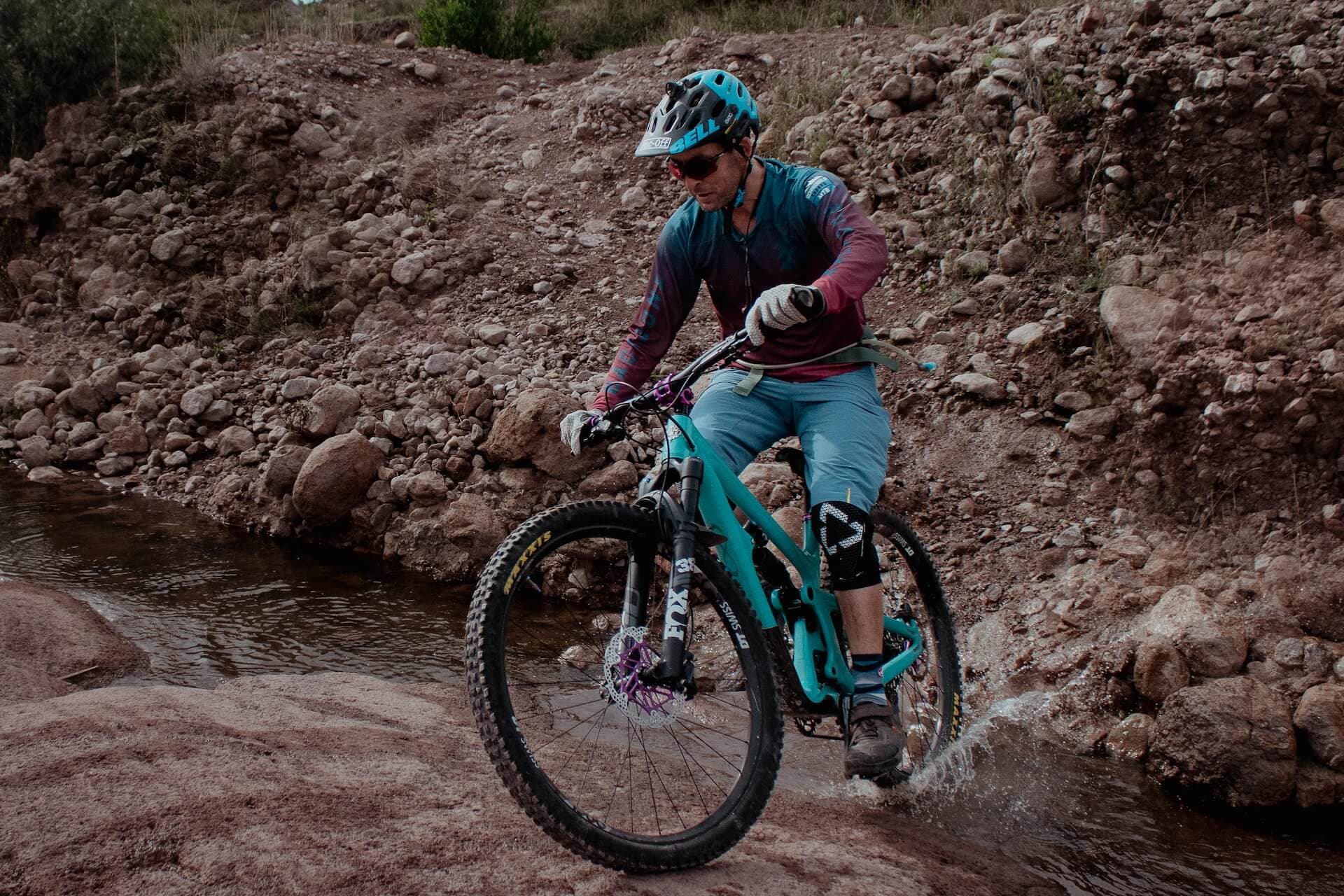 Rider crossing a shallow river over wet rock on a High Atlas trail
