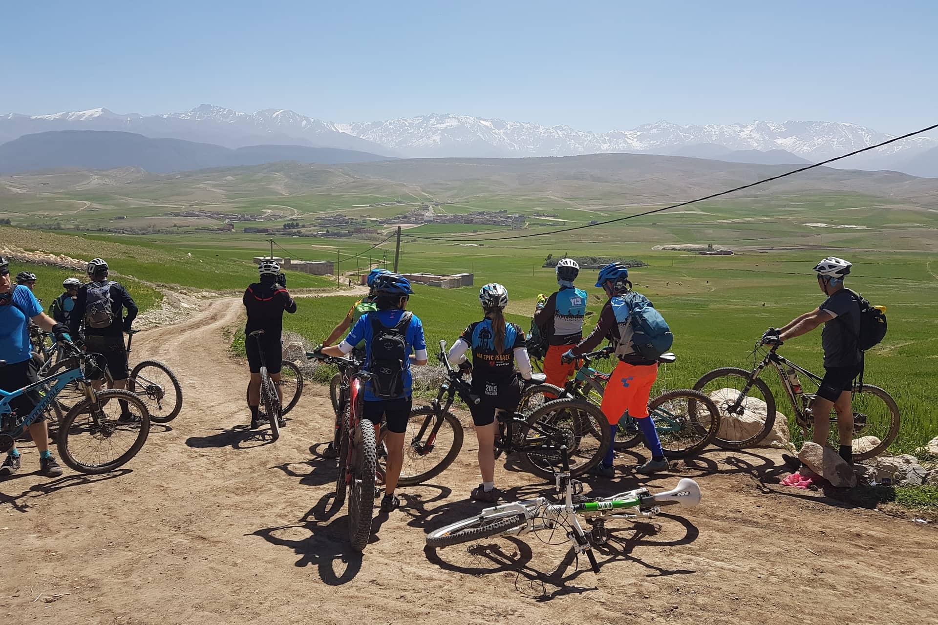 Group of riders on a piste in the foothills with the snow-covered High Atlas behind