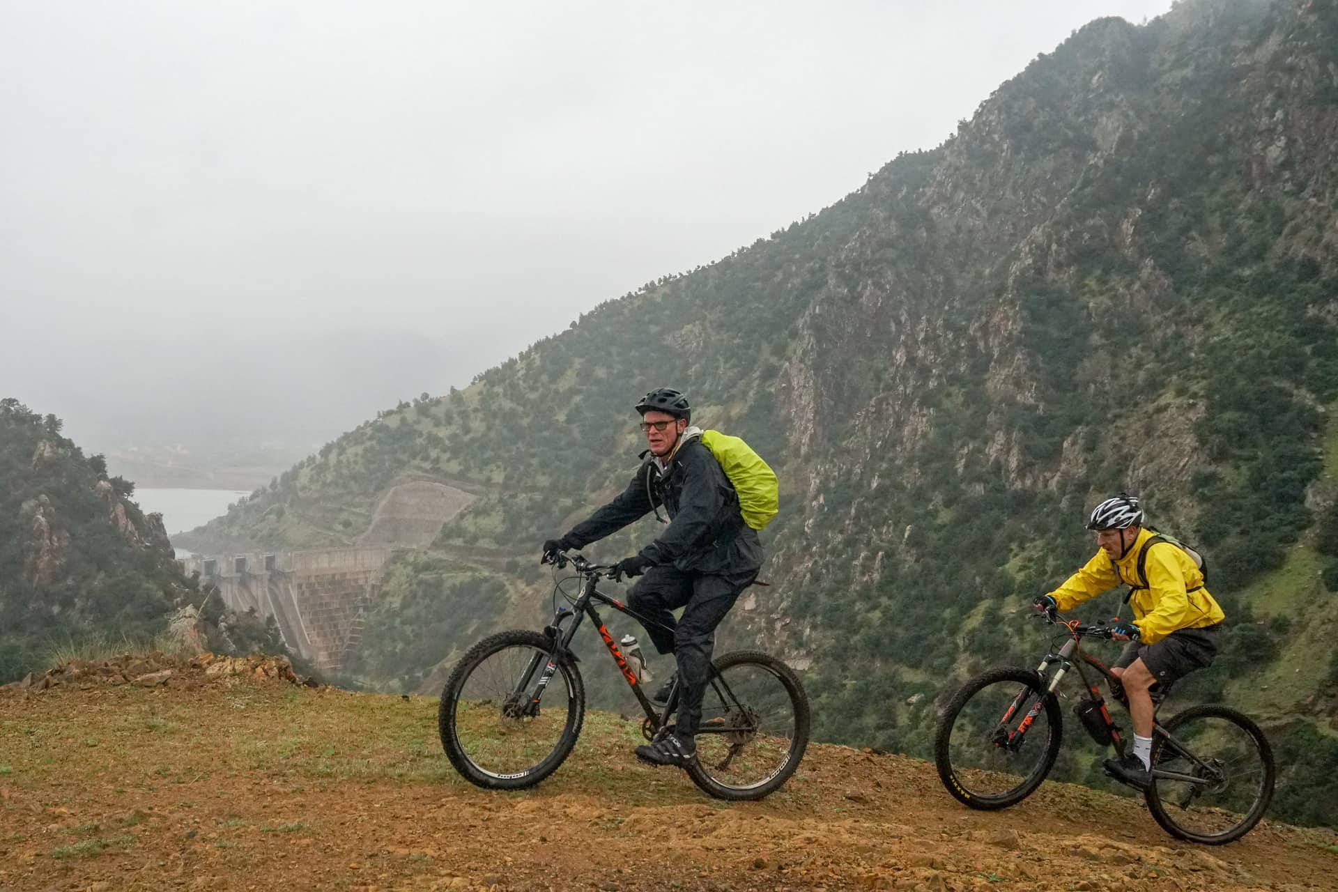Two riders on a green hillside above the Lalla Takerkoust lake