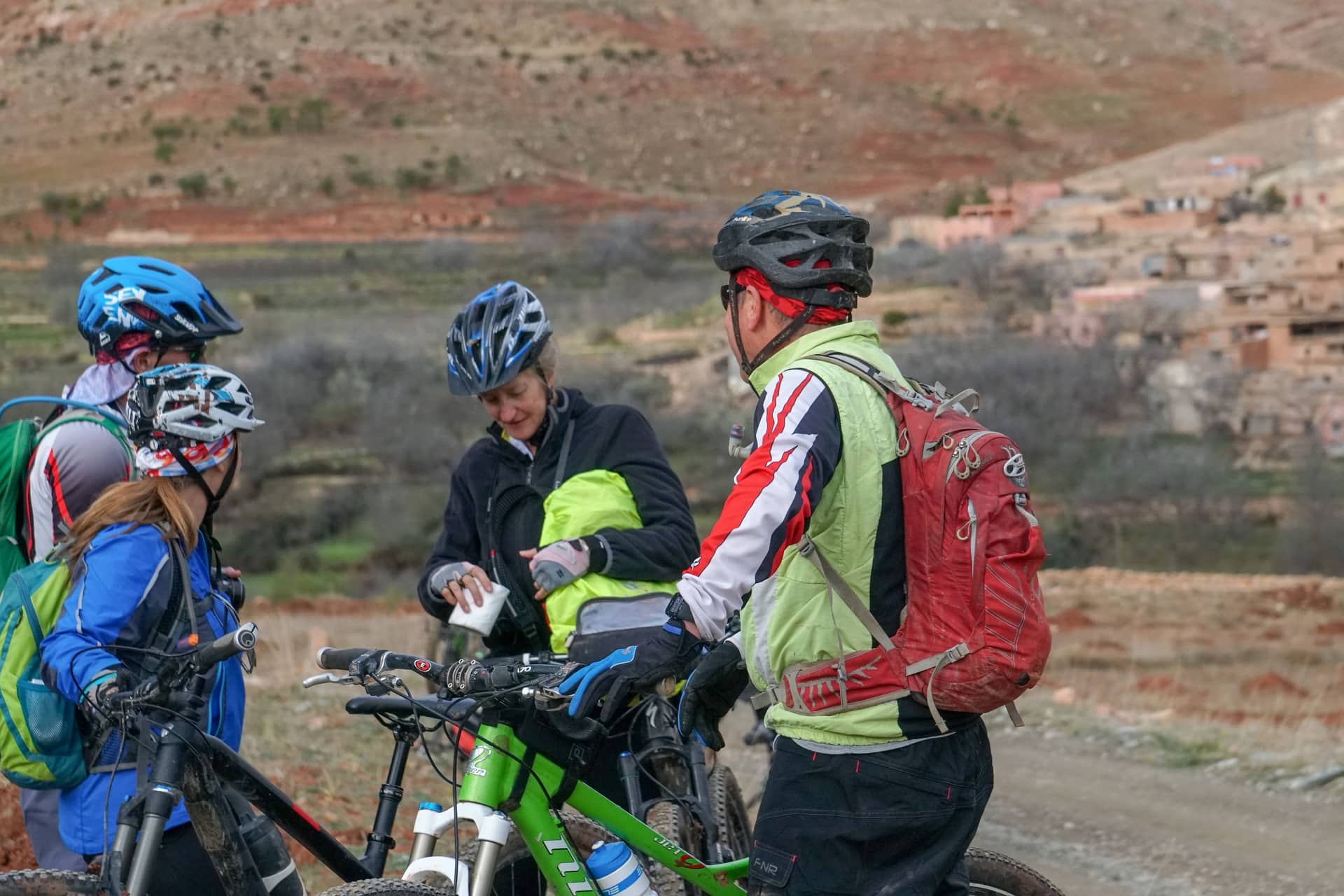 Two riders on a dirt road winding through a dry valley