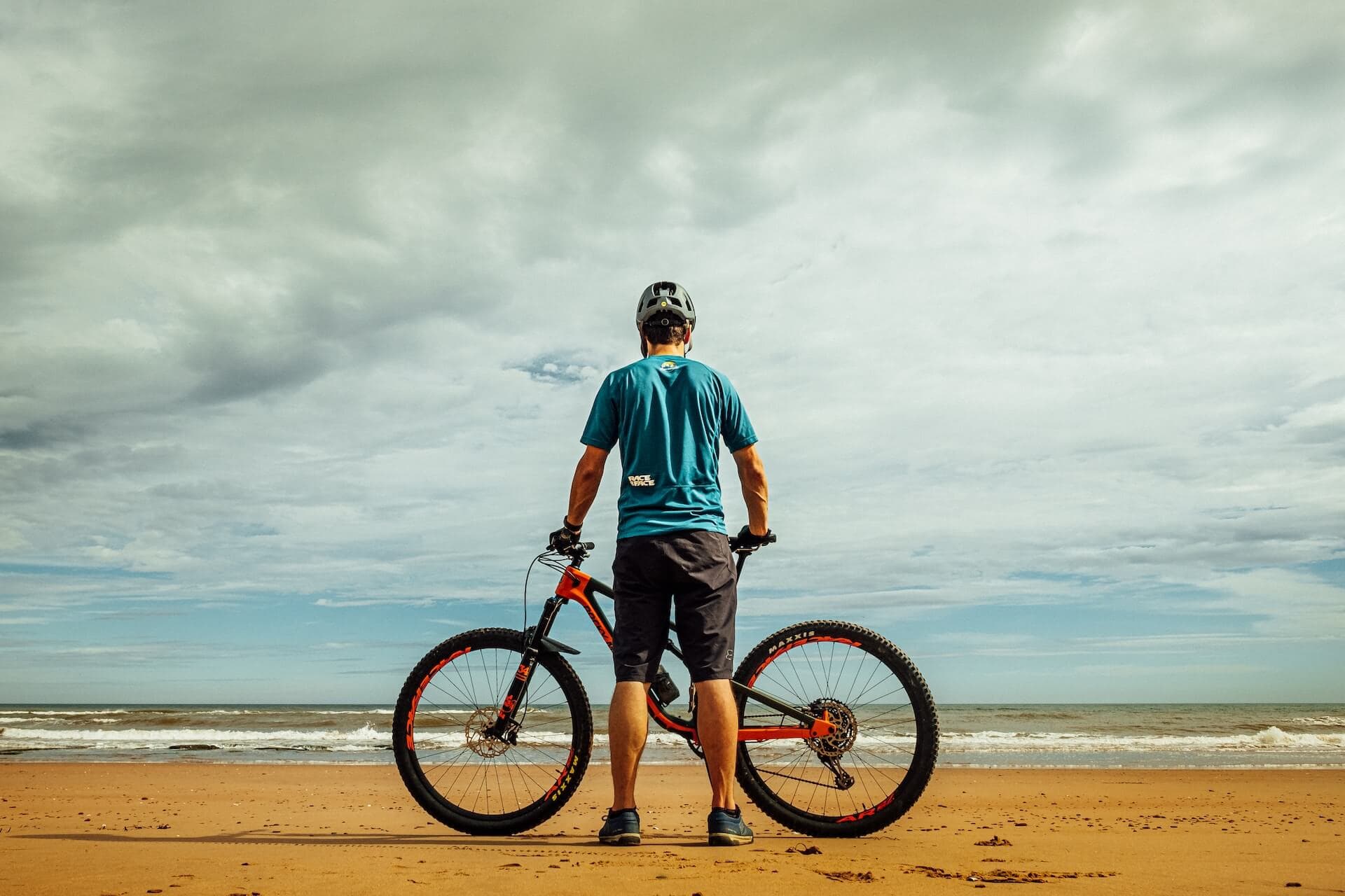 Rider standing with a mountain bike on the Atlantic beach at Essaouira