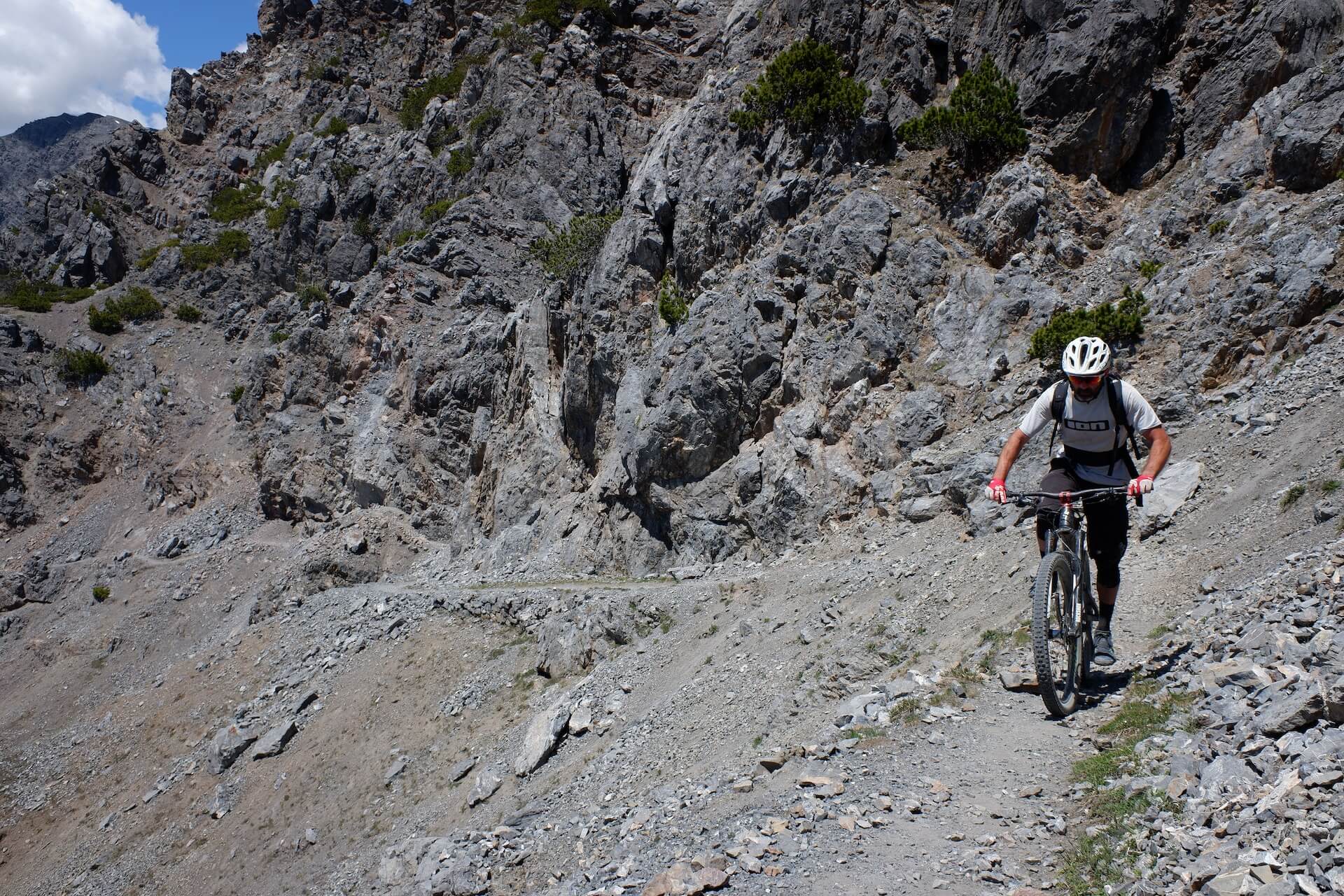 Mountain bikers riding singletrack high above an Atlas valley with snow on the peaks behind