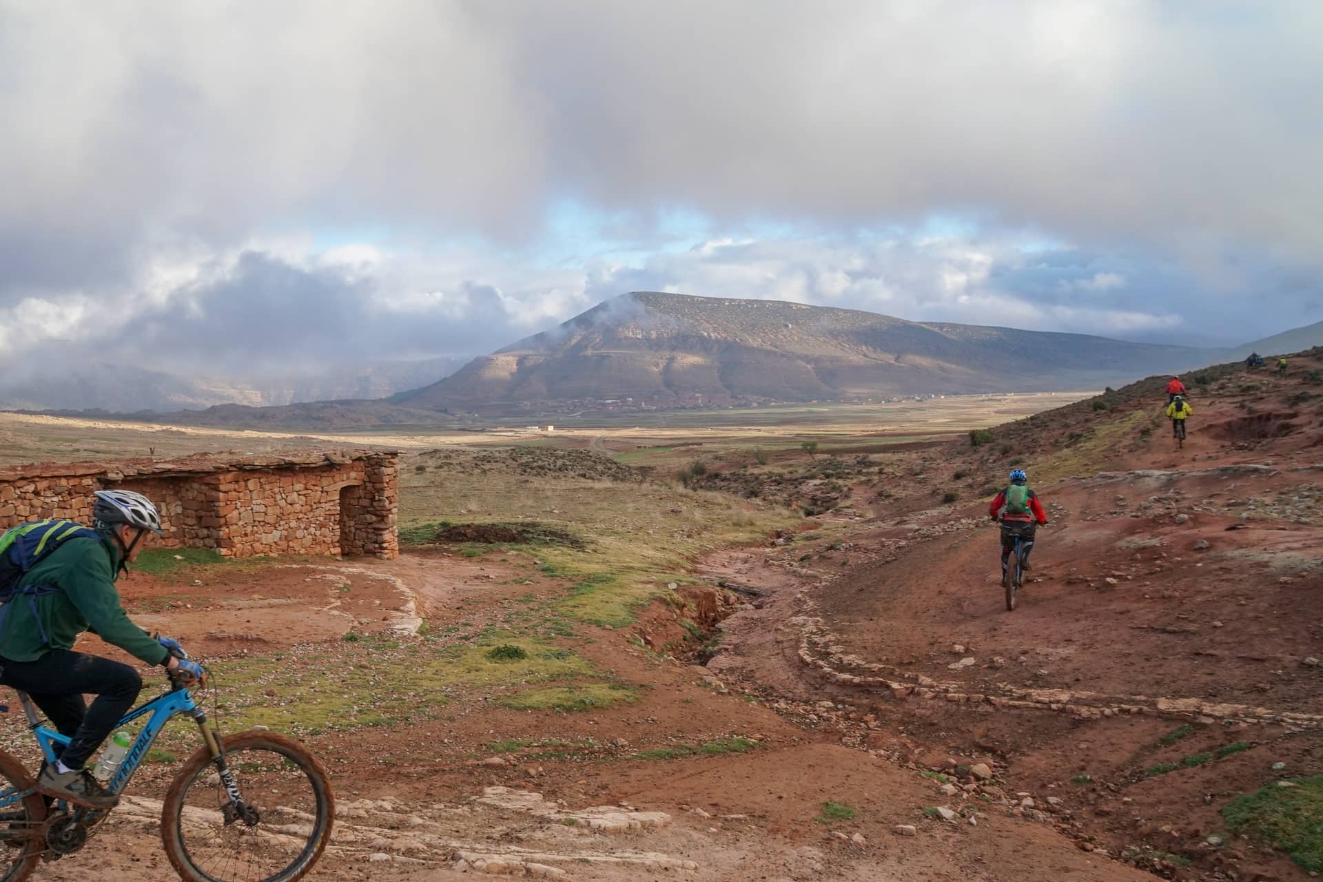 Riders on open high ground with a flat-topped plateau across the valley behind