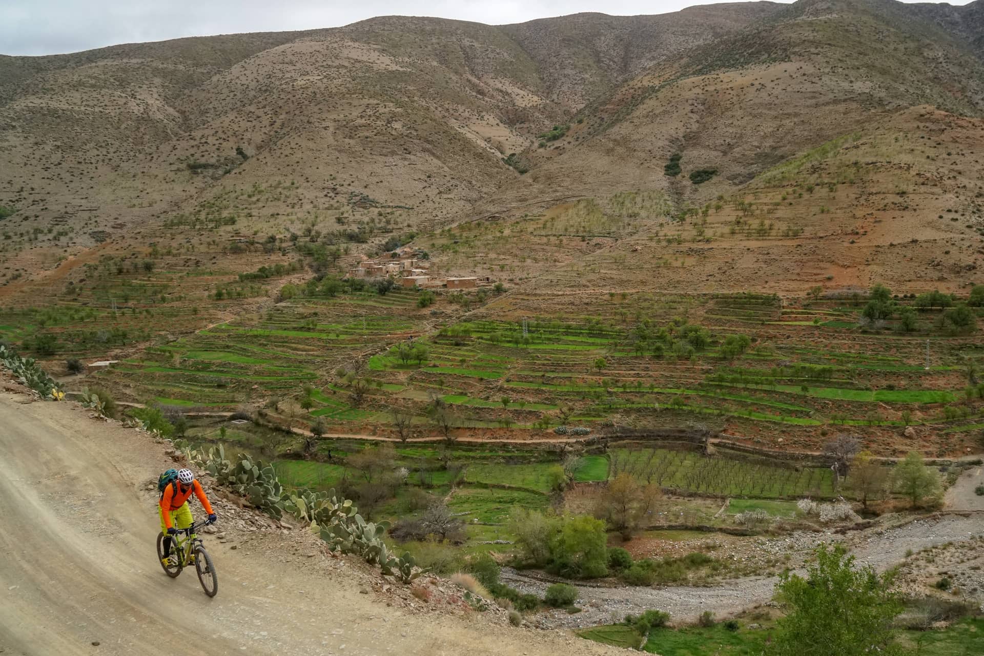 Rider on a broad piste above a terraced valley with a village on the far slope